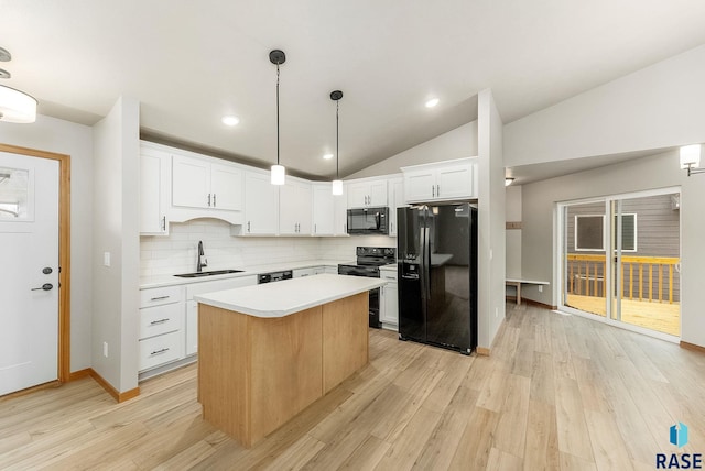 kitchen featuring vaulted ceiling, sink, white cabinetry, a center island, and black appliances