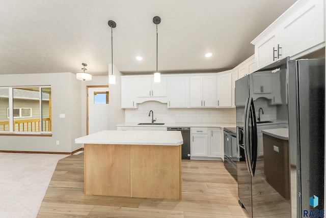 kitchen featuring pendant lighting, white cabinets, black appliances, a center island, and sink