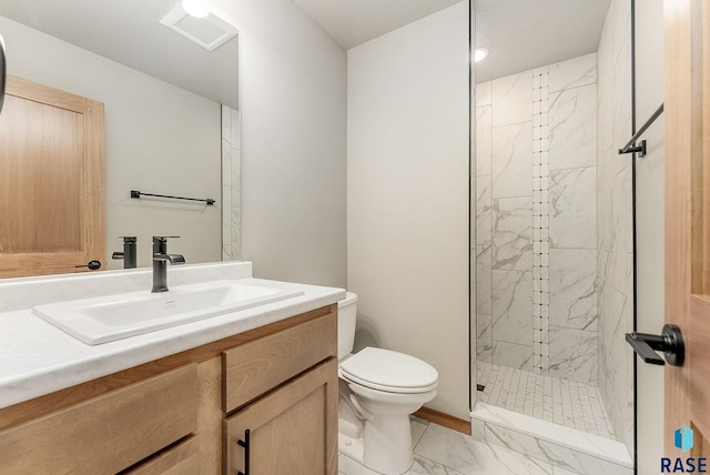 bathroom with vanity, toilet, and tiled shower