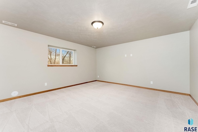 spare room featuring a textured ceiling and light carpet