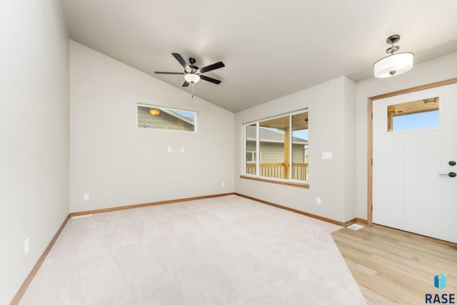 foyer entrance featuring ceiling fan, a wealth of natural light, lofted ceiling, and light wood-type flooring