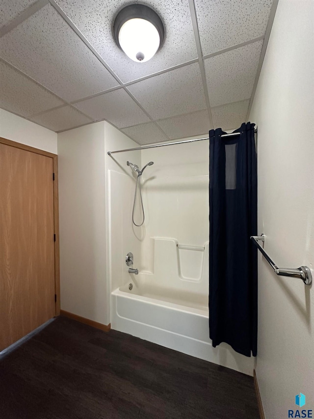 bathroom with a drop ceiling, hardwood / wood-style flooring, and tub / shower combination