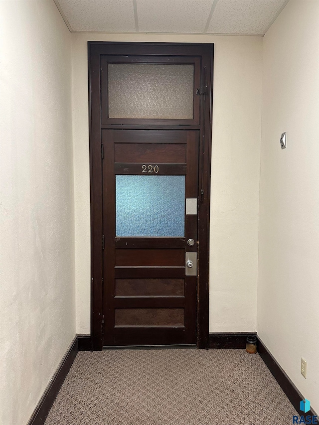 corridor with a paneled ceiling and carpet