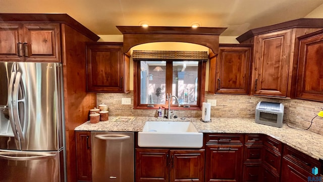 kitchen featuring stainless steel appliances, sink, tasteful backsplash, and light stone counters