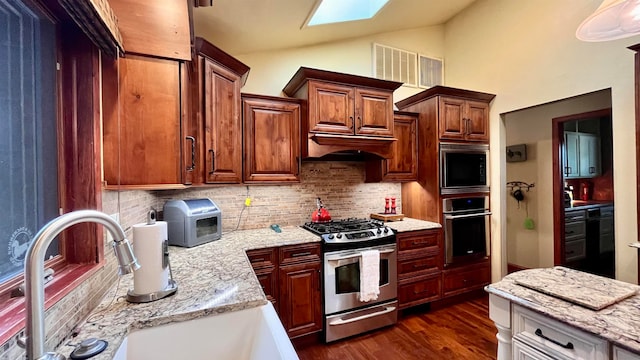 kitchen with dark hardwood / wood-style floors, stainless steel appliances, tasteful backsplash, sink, and vaulted ceiling with skylight