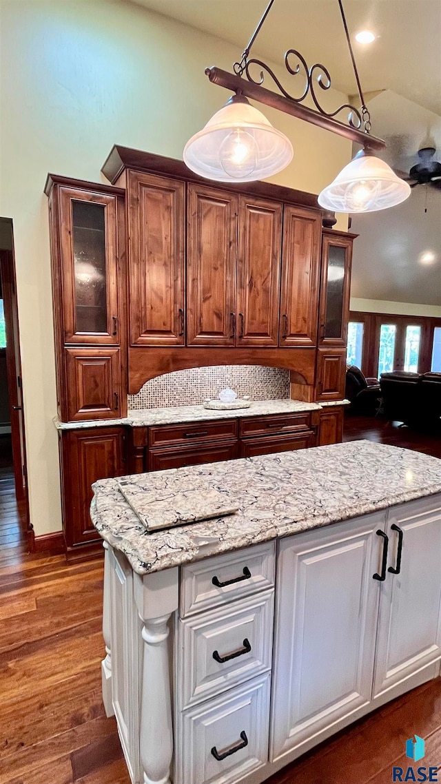 kitchen with dark hardwood / wood-style flooring, light stone counters, decorative light fixtures, and white cabinetry