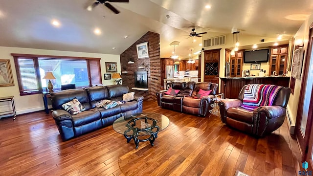 living room with ceiling fan, wood-type flooring, a brick fireplace, brick wall, and high vaulted ceiling