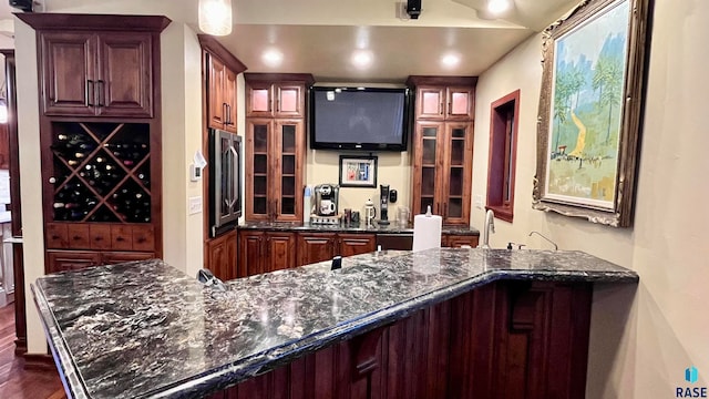 bar featuring dark stone counters and dark hardwood / wood-style floors