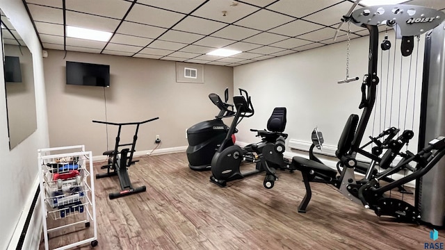 exercise area with hardwood / wood-style flooring and a drop ceiling