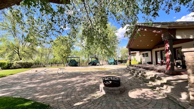 view of terrace with a playground and a fire pit