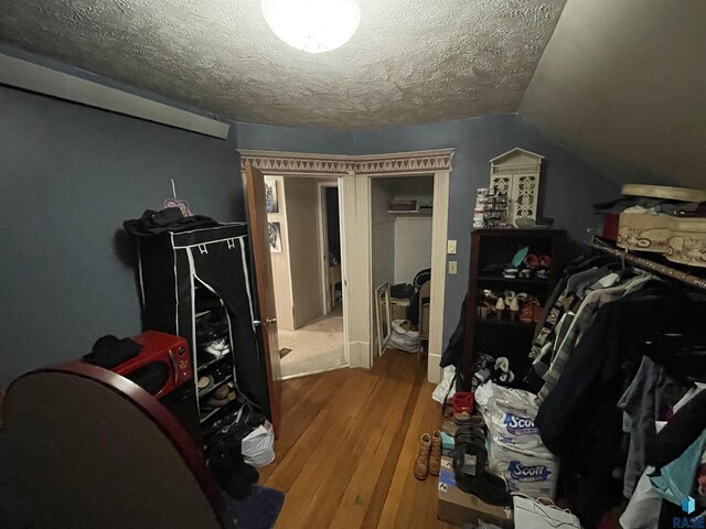 bedroom with a textured ceiling, vaulted ceiling, and hardwood / wood-style floors