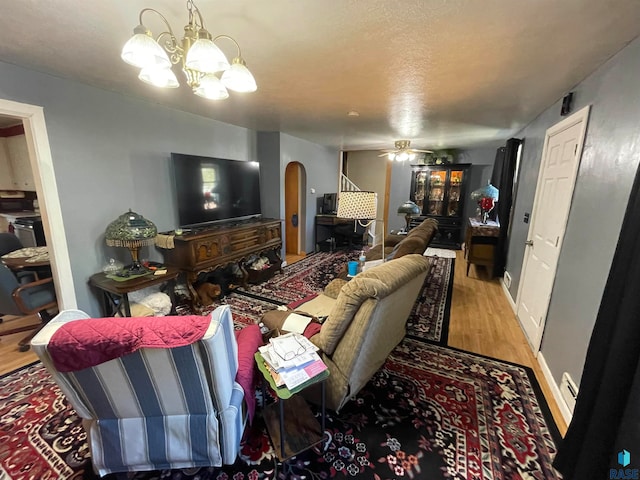 living room featuring wood-type flooring and ceiling fan with notable chandelier