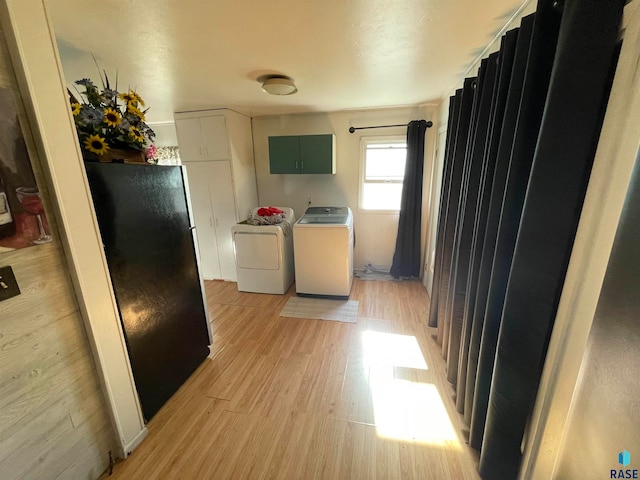 kitchen featuring black fridge, washer and dryer, light hardwood / wood-style flooring, and green cabinets