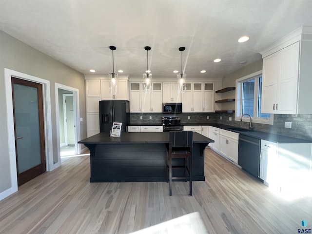 kitchen with black appliances, decorative light fixtures, a center island, and white cabinets