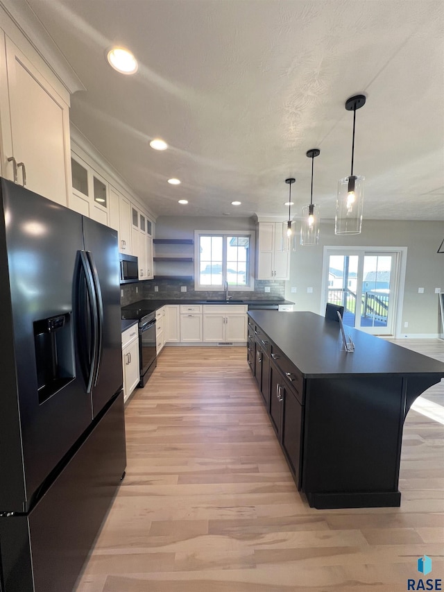 kitchen featuring decorative backsplash, a center island, white cabinets, and black appliances