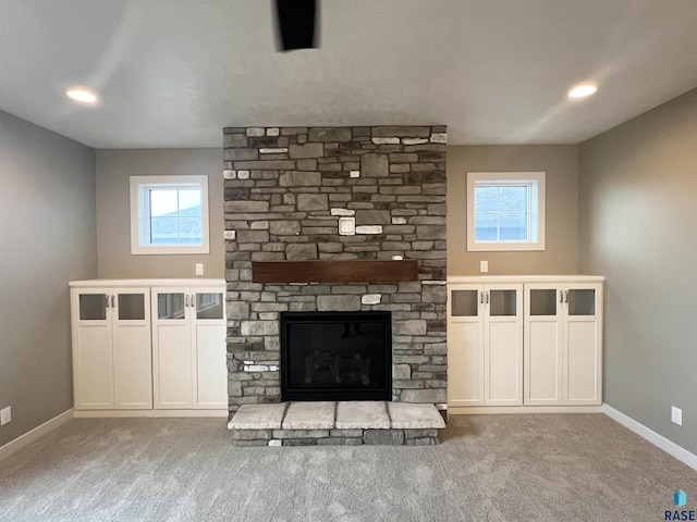 unfurnished living room featuring light colored carpet and a stone fireplace