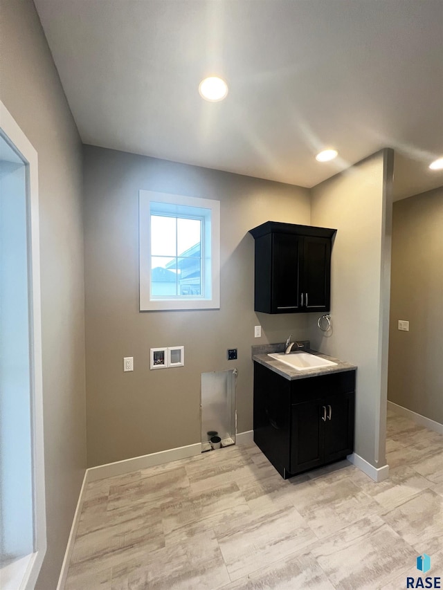 clothes washing area with cabinets, hookup for a washing machine, and sink