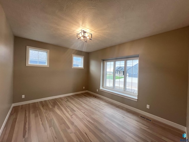 unfurnished room with a textured ceiling and light hardwood / wood-style flooring