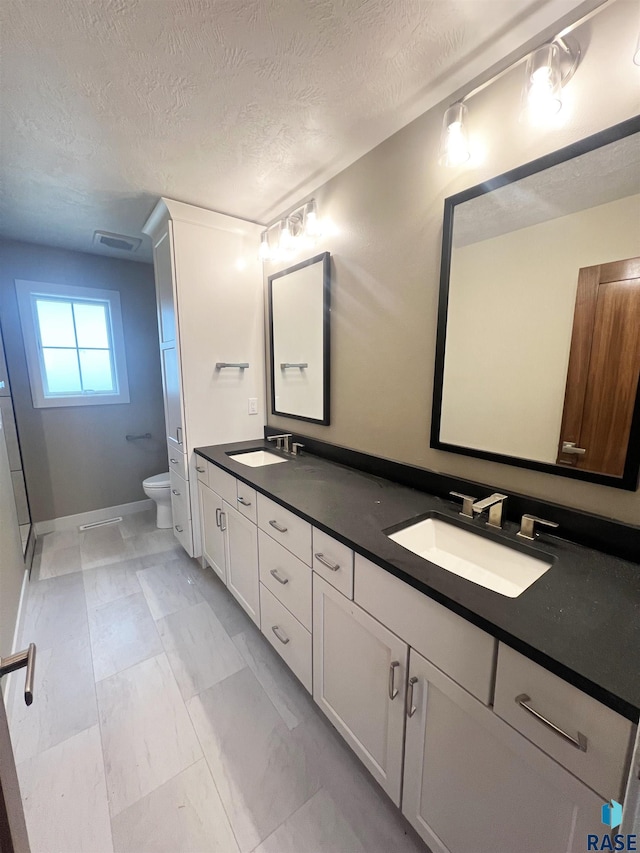 bathroom with vanity, a textured ceiling, and toilet