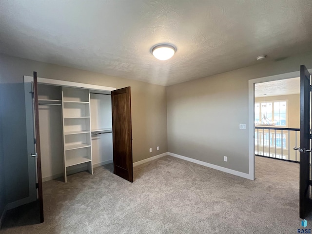 unfurnished bedroom featuring light carpet, a closet, and a textured ceiling