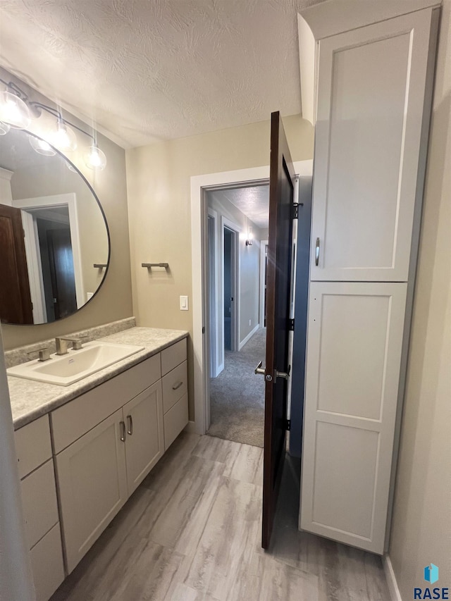 bathroom featuring hardwood / wood-style floors, vanity, and a textured ceiling