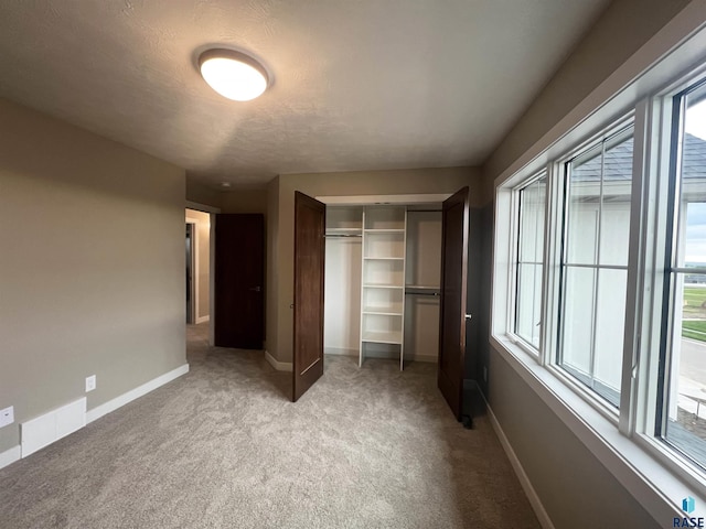 unfurnished bedroom with light colored carpet and a closet