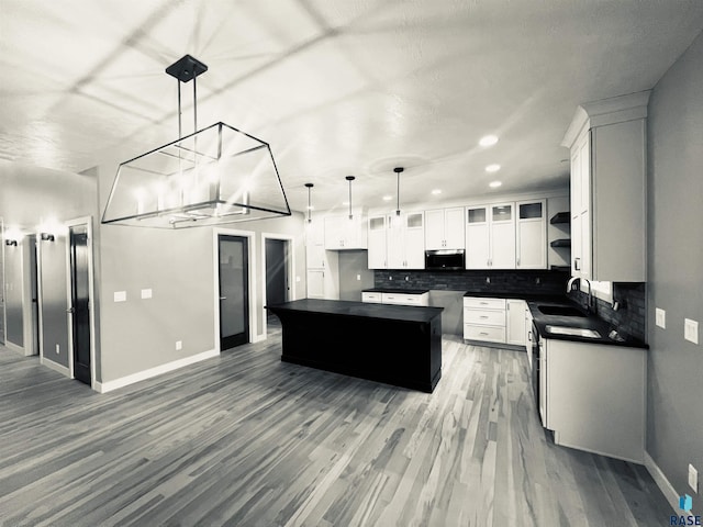 kitchen featuring pendant lighting, a center island, sink, dark hardwood / wood-style floors, and white cabinetry