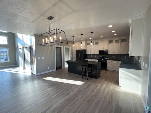 kitchen with tasteful backsplash, sink, black appliances, a center island, and hanging light fixtures