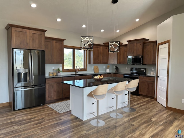 kitchen with sink, hanging light fixtures, vaulted ceiling, a kitchen island, and stainless steel appliances