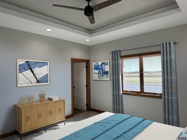 carpeted bedroom featuring a raised ceiling and ceiling fan