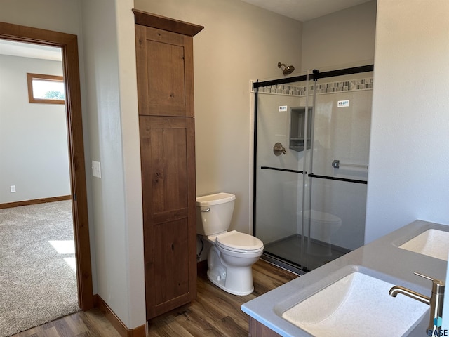 bathroom featuring toilet, an enclosed shower, wood-type flooring, and sink