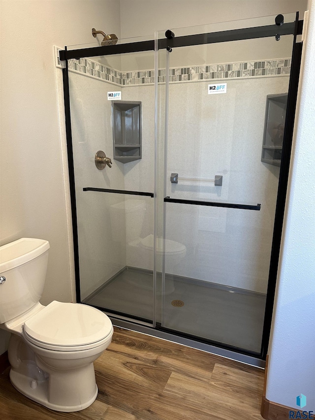 bathroom featuring walk in shower, toilet, and hardwood / wood-style flooring