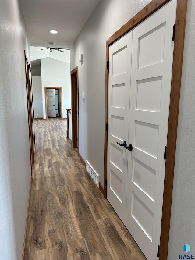 corridor with dark wood-type flooring and lofted ceiling