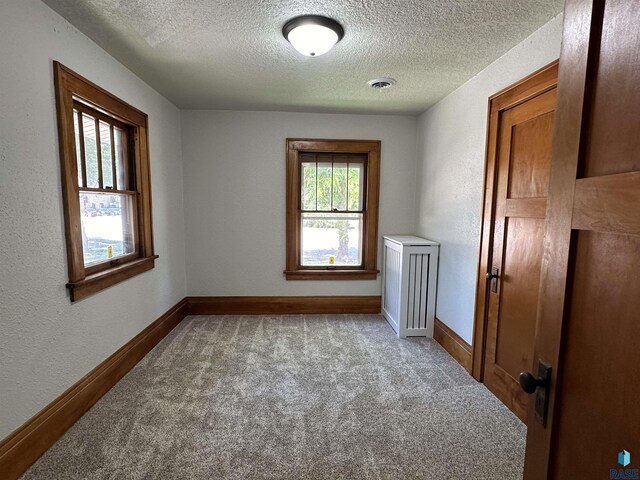 laundry room with separate washer and dryer, a textured ceiling, and carpet