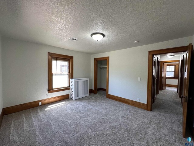 carpeted empty room with radiator and a textured ceiling