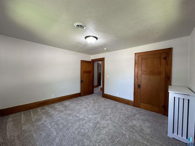 unfurnished room with a textured ceiling and carpet flooring