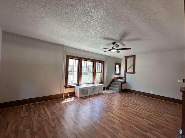 unfurnished living room with dark wood-type flooring, ceiling fan, radiator heating unit, and a textured ceiling