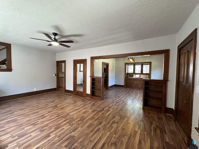 empty room with a textured ceiling, ceiling fan, and dark hardwood / wood-style floors