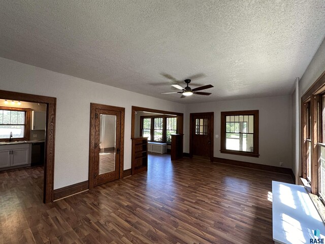 unfurnished living room with ceiling fan, dark hardwood / wood-style floors, a textured ceiling, and sink