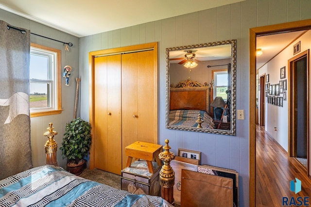 bedroom with wooden walls, a closet, and dark wood-type flooring