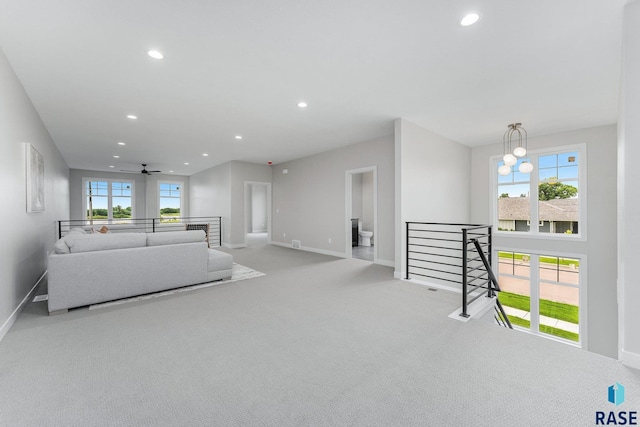 carpeted living room with ceiling fan with notable chandelier