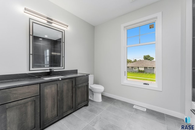 bathroom with tile patterned floors, walk in shower, vanity, and toilet