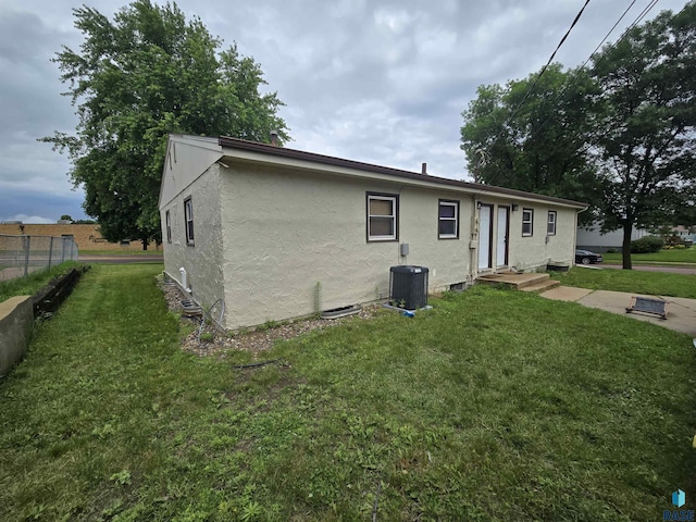 rear view of house featuring central AC unit and a yard