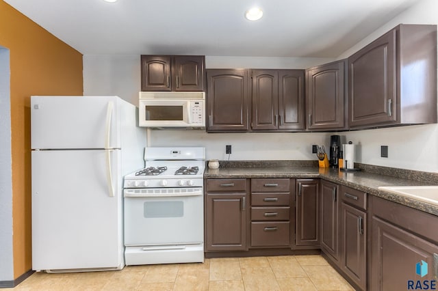 kitchen featuring dark brown cabinetry, white appliances, sink, and light tile patterned floors