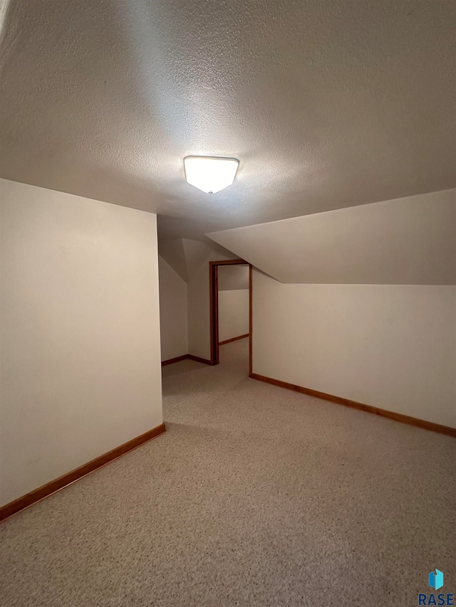 bonus room featuring carpet, a textured ceiling, and lofted ceiling