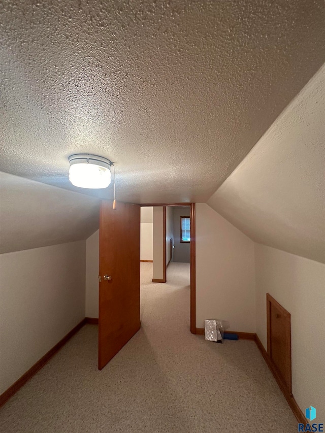 bonus room with a textured ceiling, lofted ceiling, and carpet floors