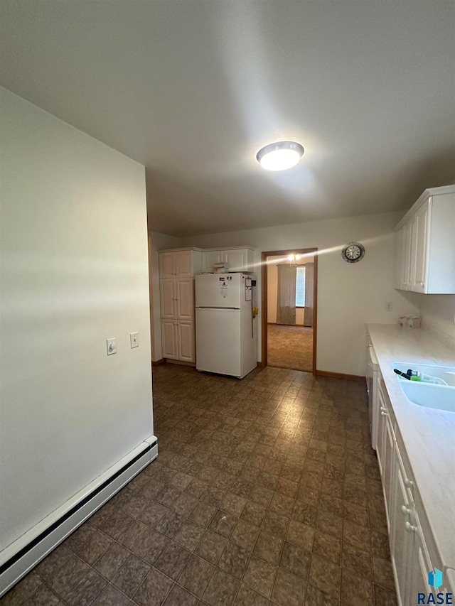 kitchen featuring white fridge, a baseboard heating unit, sink, white cabinets, and dark tile floors