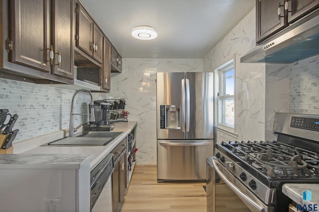 kitchen featuring tasteful backsplash, dark brown cabinetry, stainless steel appliances, sink, and light hardwood / wood-style floors