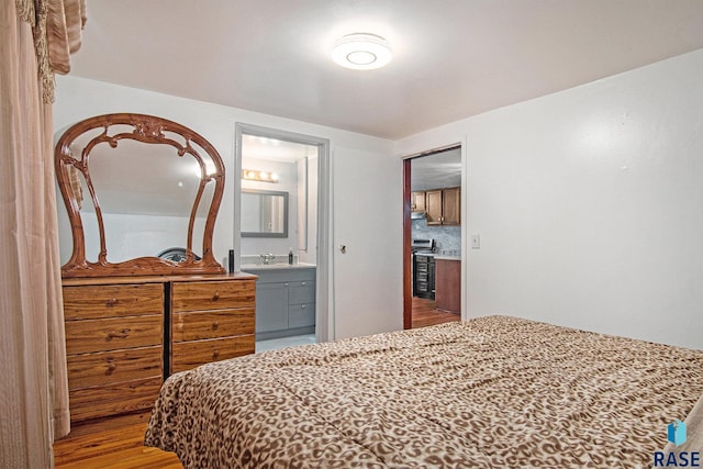 bedroom with ensuite bathroom and hardwood / wood-style flooring