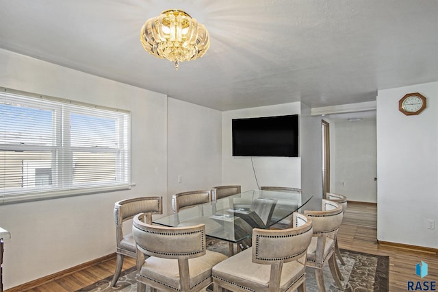 dining space with wood-type flooring and a notable chandelier